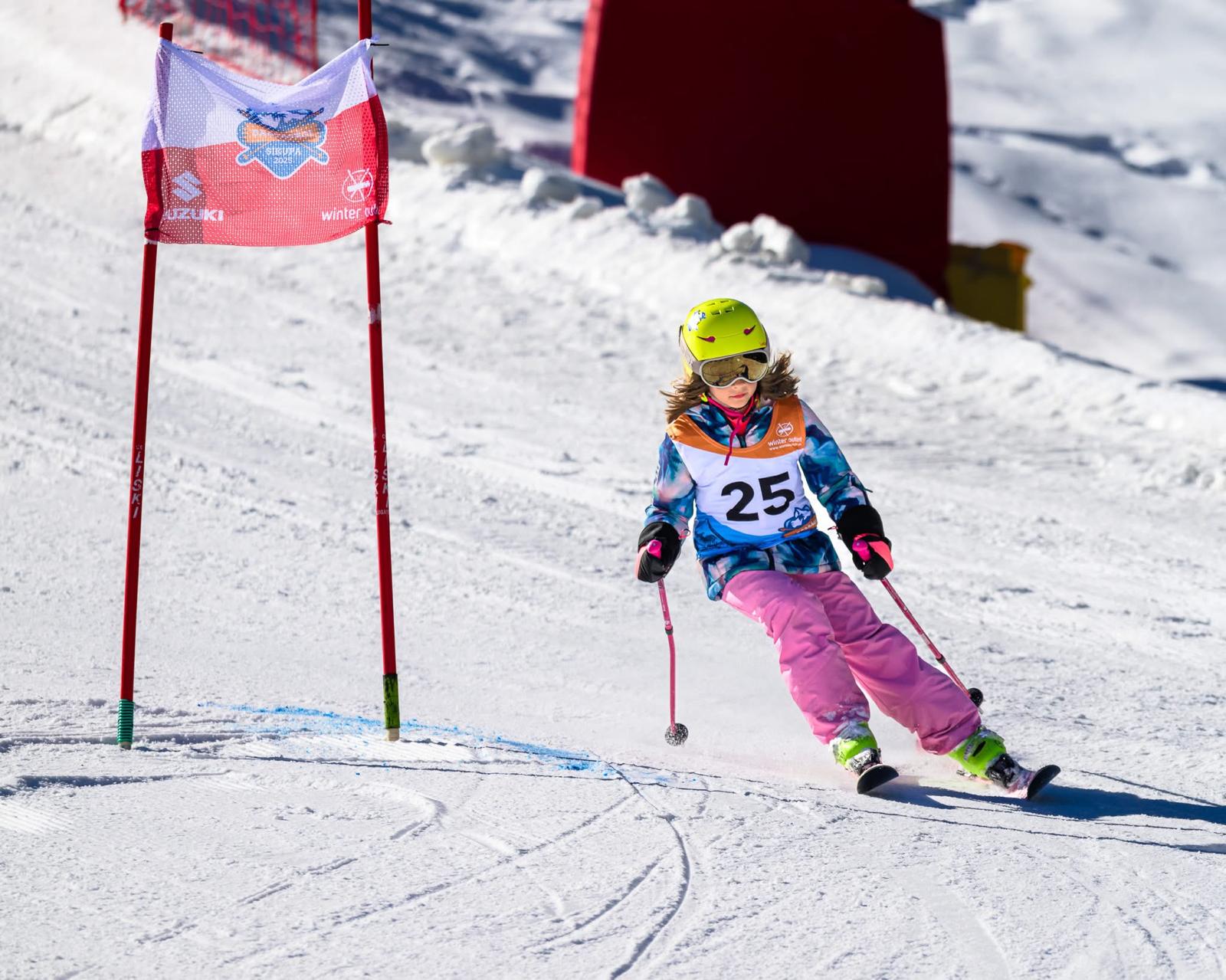 A young ski racer carving through a slalom gate